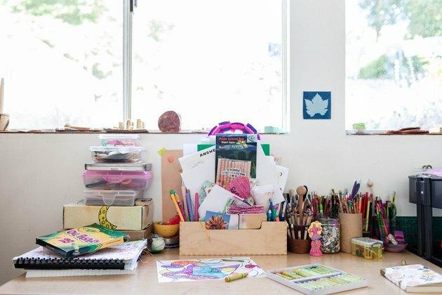 Une table d'art pour enfants avec diverses fournitures face aux fenêtres