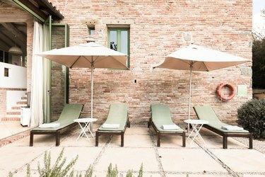 Groene lounge stoelen en parasols tegen bakstenen muur