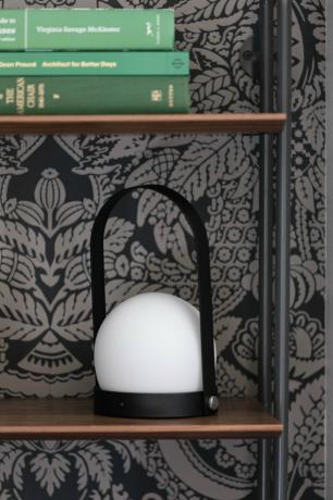 مصباح LED محمول بالقائمة على خزانة الكتب بجوار خلفية منقوشة