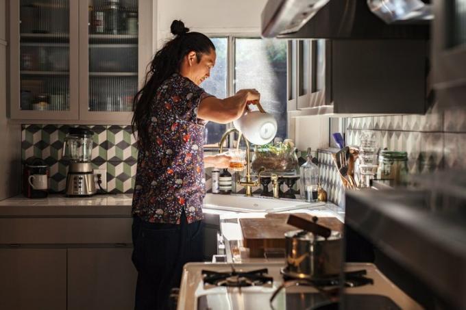 Sato si versa il tè in cucina