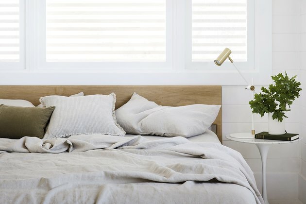 cama com roupa de cama Cultiver na cama com cabeceira de madeira