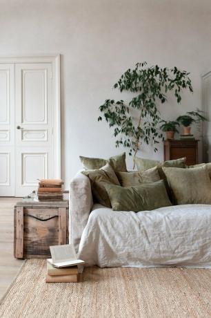 natuurlijk decor in een grijze kamer met linnen bank en groene kussens