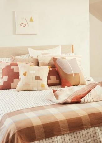 Textiles rosas y neutros en la cama.