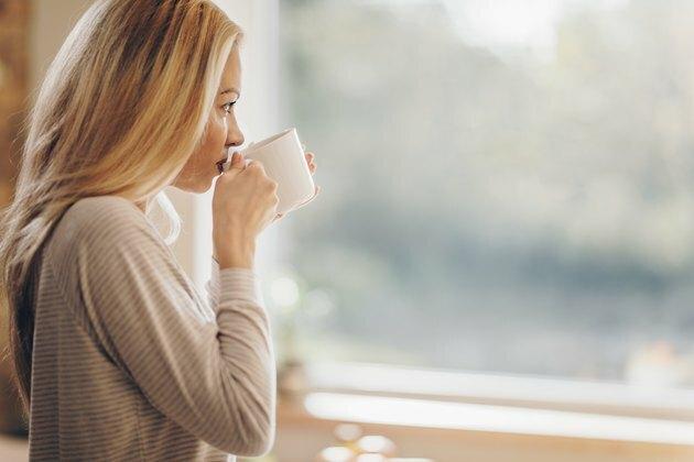 Profielmening van peinzende vrouw het drinken ochtendkoffie thuis.