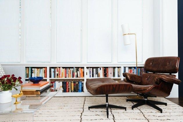 Namų biuras, pastatytas bibliotekoje su ruda odine kėde ir ottomanu