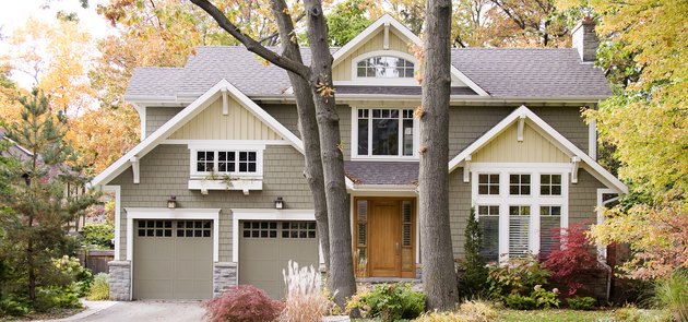 Lichtgroen en crème Craftsman huis exterieur met witte rand omgeven door bomen