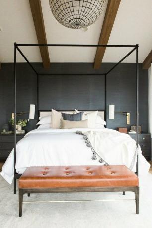 donkere minimalistische slaapkamer met bruinleren bank en hemelbed,