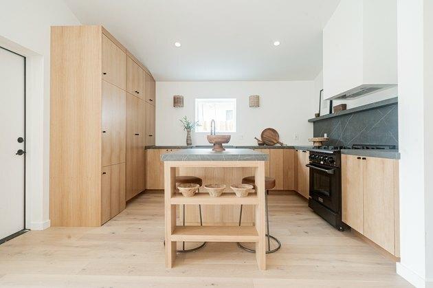Armários altos de madeira com backsplash de mármore cinza verde na cozinha