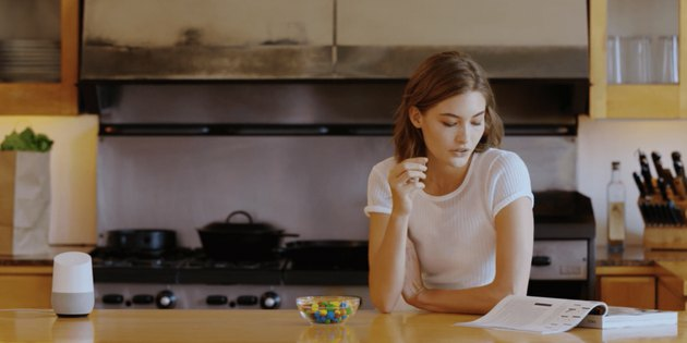 vrouw en Google Home-apparaat in de keuken