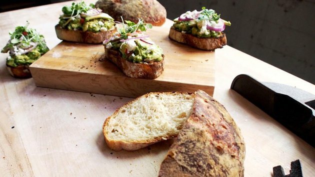 avocadotoost op vers gebakken brood dat op houten raad wordt gehakt