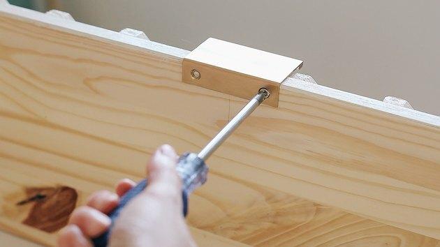 Mão usando uma chave de fenda na cômoda de madeira IKEA