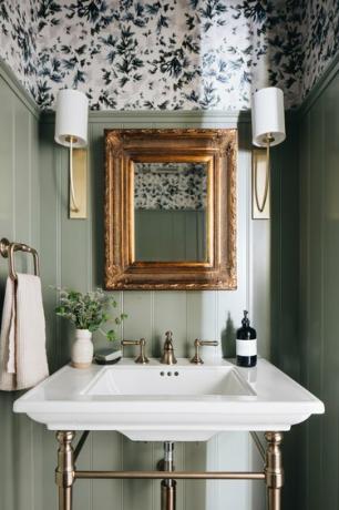 حمام مع حوض أبيض ومرآة ومصباحين مطلي باللون الأخضر الفاتح مع منطقة علوية منقوشة