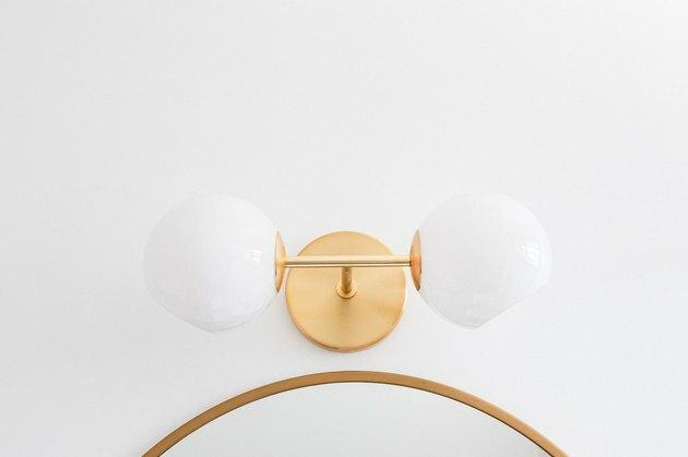 Arandela de parede de ouro com globos sobre um espelho