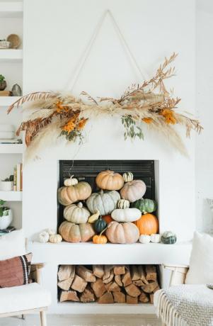 Rustieke herfst decor op schoorsteenmantel met natuurlijke muur opknoping en pompoenen