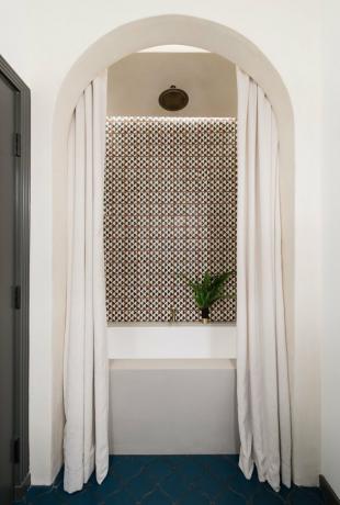 banheiro branco com backsplash estampado, piso em arco e azul marinho