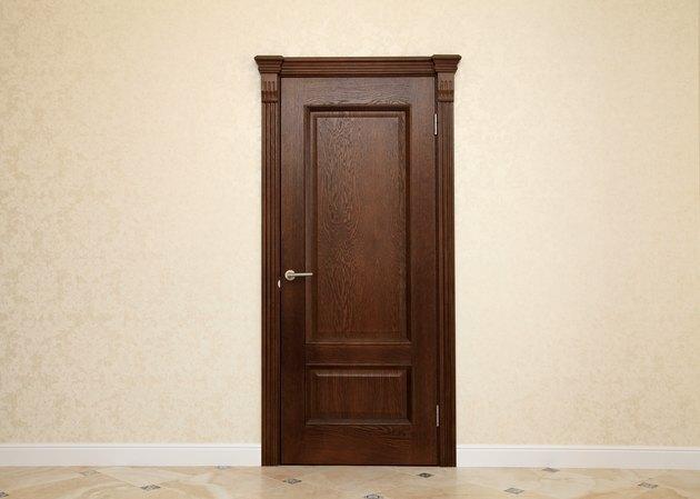 tuščias smėlio spalvos kambario interjeras su rudomis medinėmis durimis