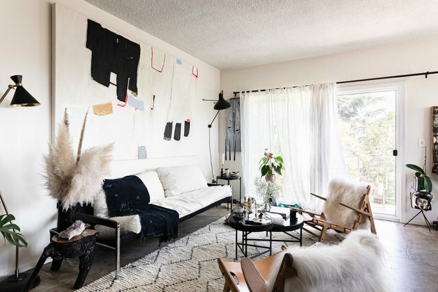 sala de estar con pisos de concreto, puertas francesas con cortinas de gasa, arte en la pared