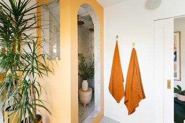 valkoinen kylpyhuone okkeriseinillä ja oranssilla pyyhkeillä