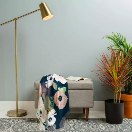 pufe com manta floral e lâmpada e plantas próximas