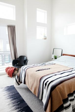 soveværelse med områdets tæppe og accentstol og mønstret kast på sengen