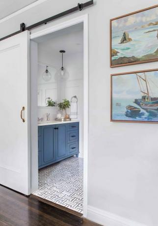 Pequena porta deslizante branca do banheiro com penteadeira azul e ladrilho estampado