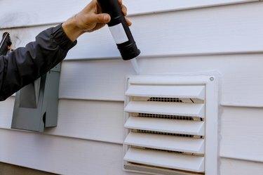 Ventilador de exaustão do secador na lateral da casa com acabamento em plástico branco com silicone