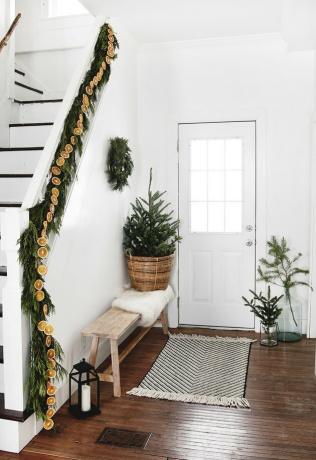 cores de Natal branco e verde na entrada com guirlandas e mini árvore nas escadas
