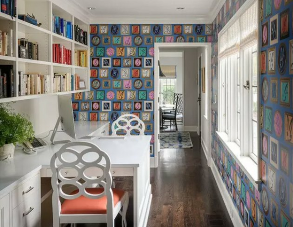 Home Office for Two White construído em uma mesa frente a frente com estantes de livros e papel de parede.