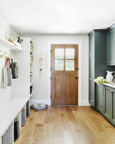 armazenamento de mudroom verde floresta e branco com piso de pinho