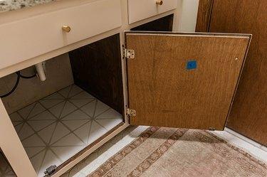 Отворена дървена врата на шкаф за баня