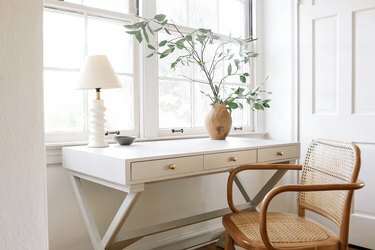 escritorio blanco con lámpara blanca geométrica y silla de madera vintage