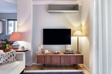Lemari kayu dengan tv datar dan lampu di ruang tamu kecil.