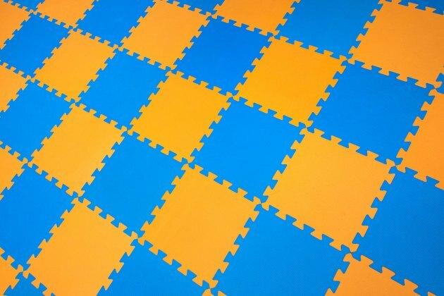 Kummist oranži-sinise värvi põrandal mõistatus. Horisontaalse paigutuse perspektiiv. Mänguväljaku siseruumides põrand.