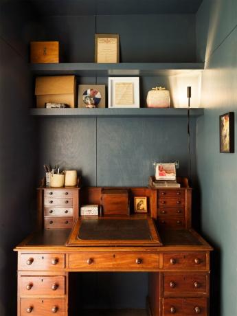 home office azul-escuro com mesa de madeira antiga