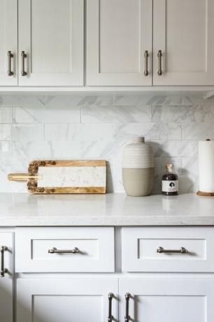Cocina minimalista con gabinetes y encimeras blancas y placa para salpicaduras de azulejos