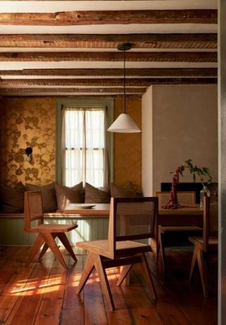 златни тапети в трапезарията с градински зелени акценти и дървени греди на тавана