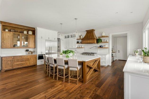 bella cucina nella nuova casa di lusso con isola, lampade a sospensione e pavimenti in legno.