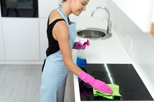 Jovem adulta, limpeza de fogão elétrico na cozinha