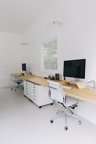 Idéias de organização de home office com duas cadeiras de escritório na estação de trabalho com mesa de madeira natural, armários de arquivo brancos sobre rodas.
