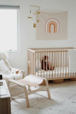 witte minimalistische kinderkamer inrichting met wieg en hangende kunst