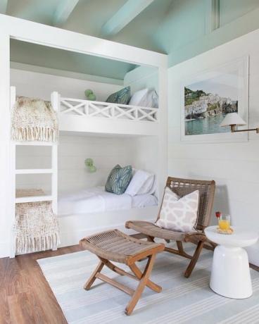 strandchique slaapkamer met witte stapelbedden en balken aan het plafond