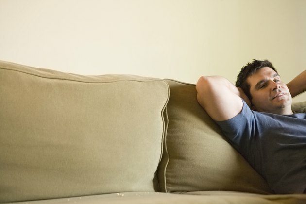Subrendęs vyras atsipalaiduoja ant sofos