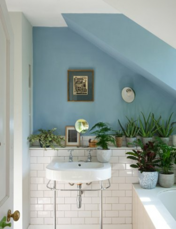 Il colore della vernice blu chiaro di Farrow & Ball su un muro del bagno con piastrelle bianche nella metà inferiore e un lavandino bianco.