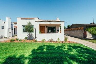 Pişmiş toprak kiremitli İspanyol tarzı bir beyaz evin ön bahçesi