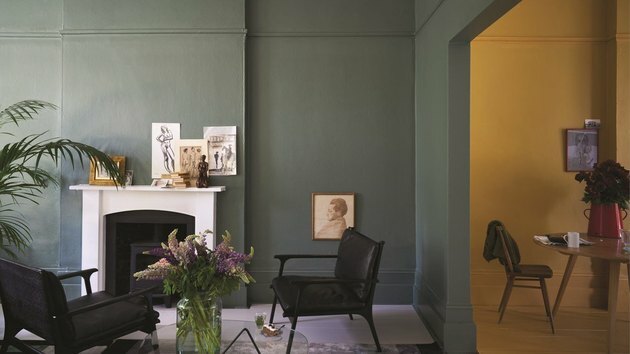 sala de estar com paredes verdes escuras e lareira branca