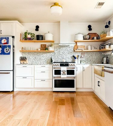 bijela suvremena kuhinja s mesinganim i matiranim rasvjetnim tijelom u središtu