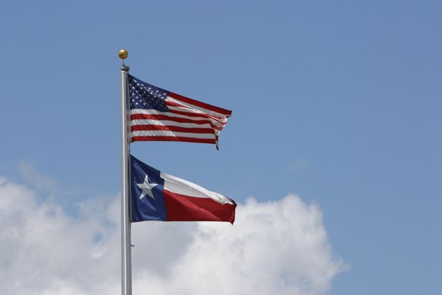 Amerikansk flagg og statsflagg i Texas på himmelen
