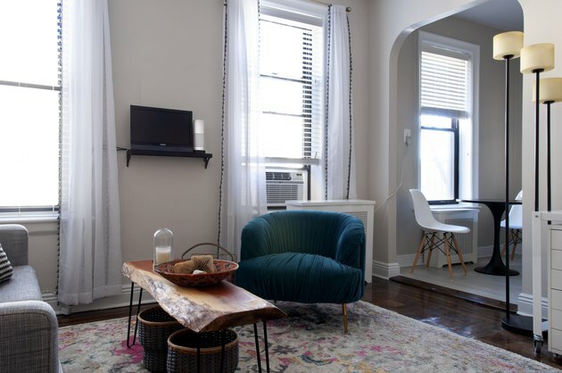 woonkamer met witte gordijnen, houten tafel en blauw fluwelen stoel