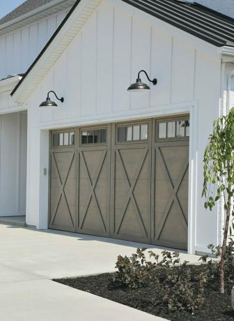 Portas de garagem de madeira cinza claro com design X e luzes de celeiro