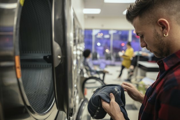 Ung mand, der kontrollerer plet på jeans ved vaskeri